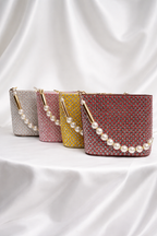 Three handbags with pearl embellishments on a white fabric background