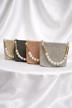 Four handbags with pearl embellishments on a white fabric background