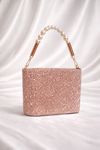 Sparkly handbag with pearl handle on a satin background