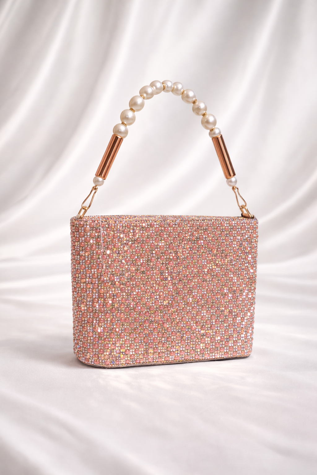 Sparkly handbag with pearl handle on a satin background