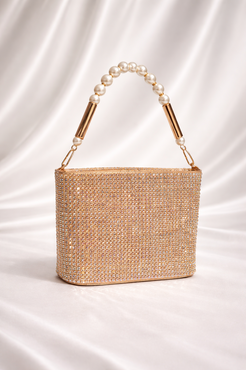 Gold beaded handbag with pearl handle on a white satin background