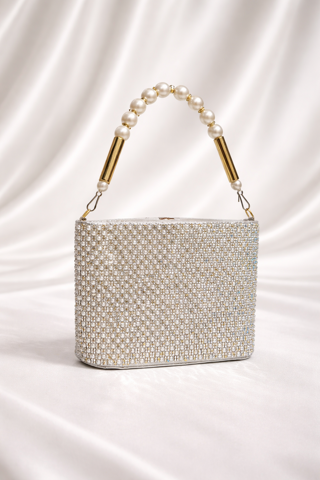 Silver beaded handbag with pearl handle on a satin background