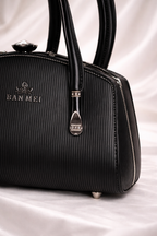 Black gunmetal crescent moon rings and vertical stripe texture on luxury black bag
