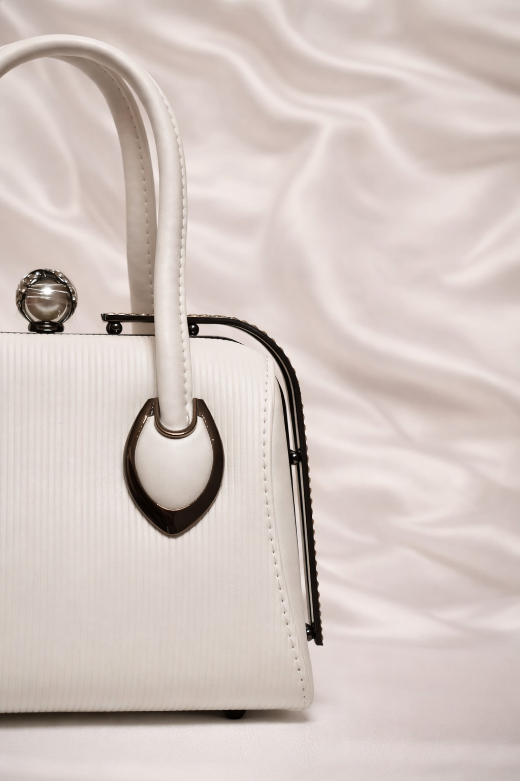 Close-up of rhinestone frame and pearl connector handles on Silslah white handbag