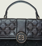 Black quilted handbag with a brand logo on a light gray background