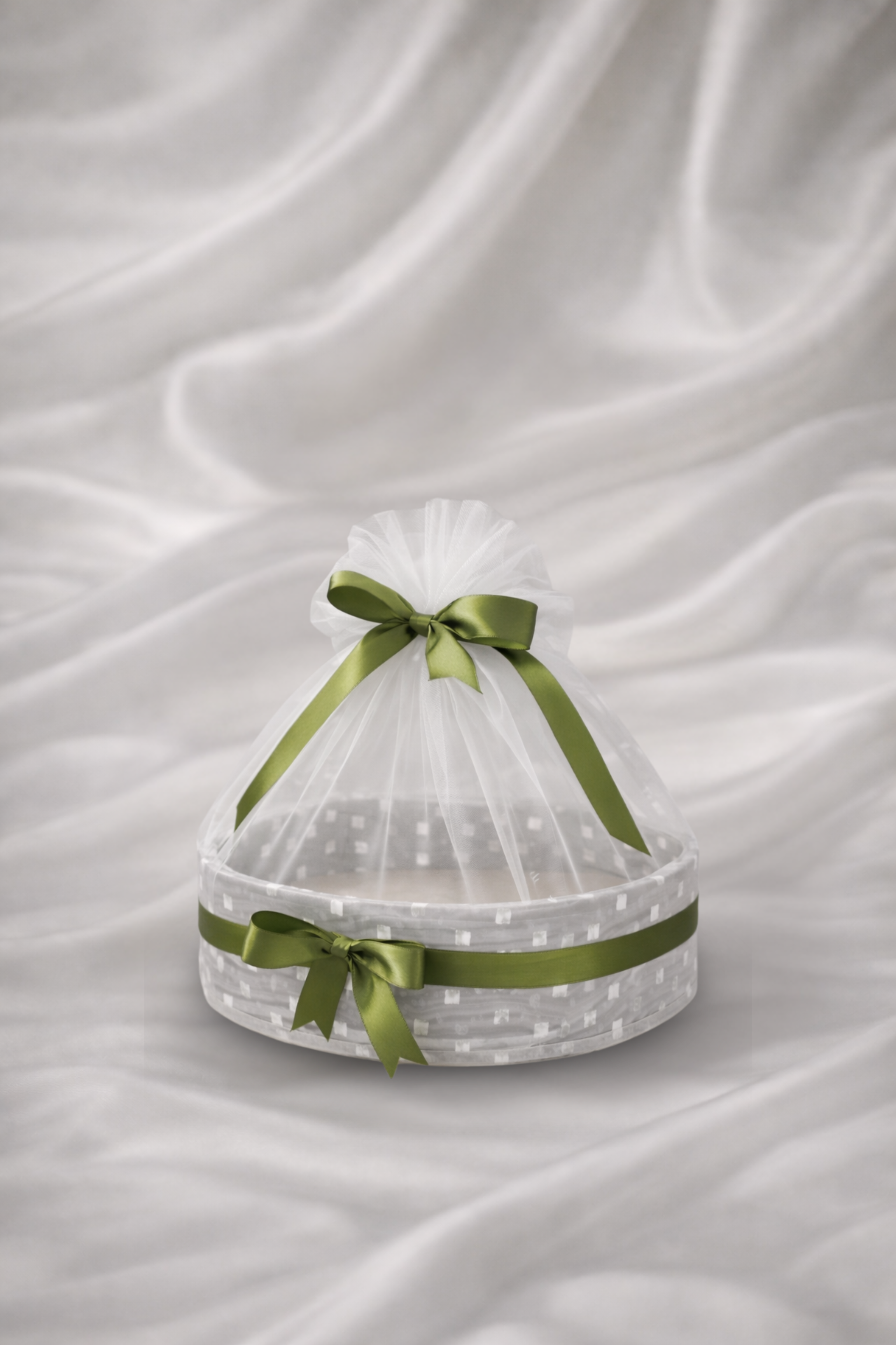 Clear plastic basket with green ribbons on a white fabric background