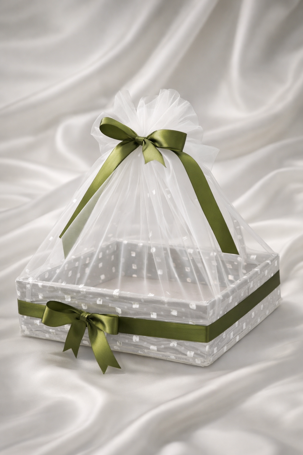 Decorative box with green ribbons on a white fabric background