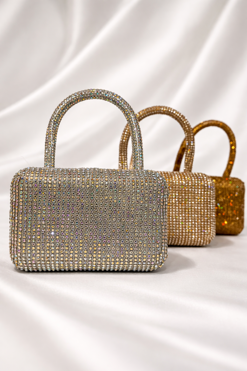 Three glittery handbags in silver, gold, and bronze on a white background