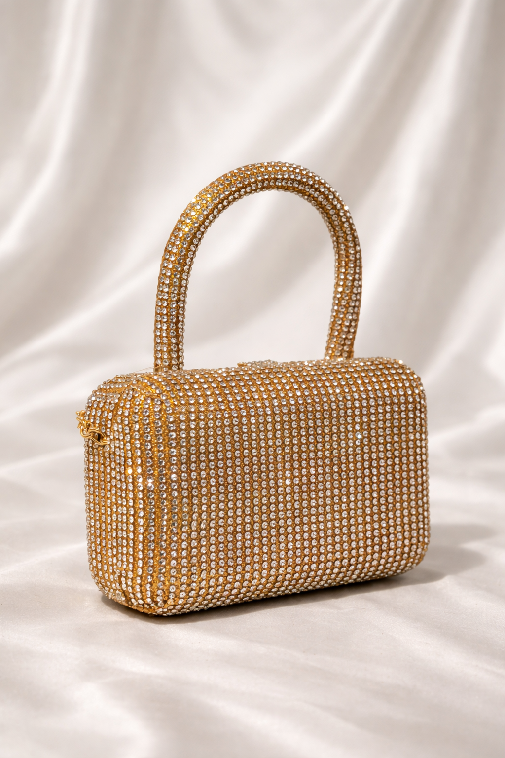 Gold beaded handbag on a white fabric background