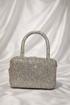 Silver handbag with rhinestone embellishments on a white fabric background