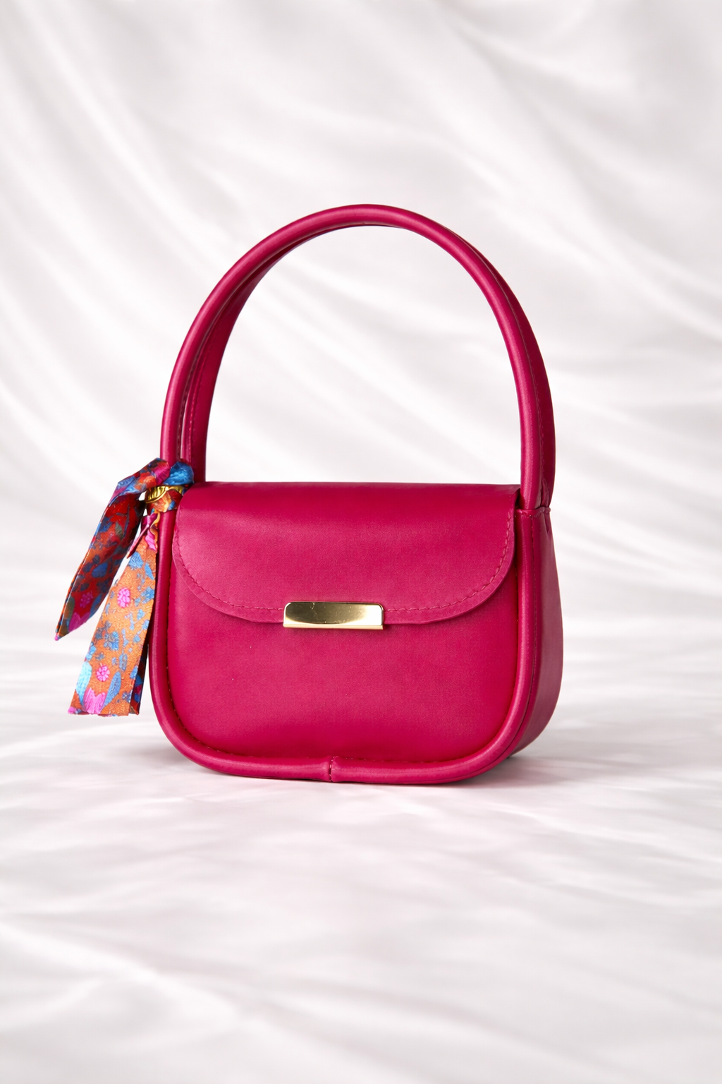 Close up of a Silslah mini handbag with silk scarf on handle and gold flap