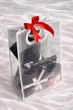 Clear gift bag with black shoes, red bow, and white text on a white background