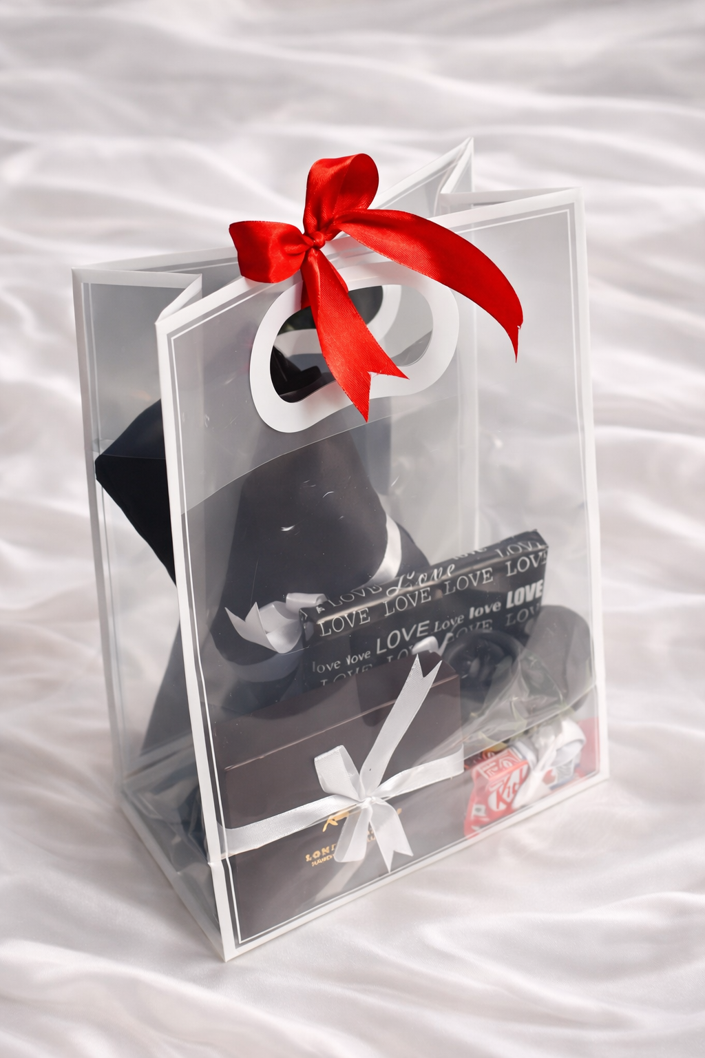Clear gift bag with black shoes, red bow, and white text on a white background