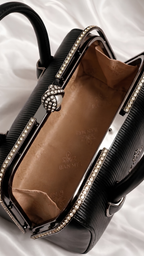Spacious interior of black leather bag showing warm brown lining and metal frame